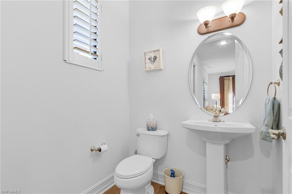 Bathroom featuring toilet, baseboards, plenty of natural light, and wood finished floors