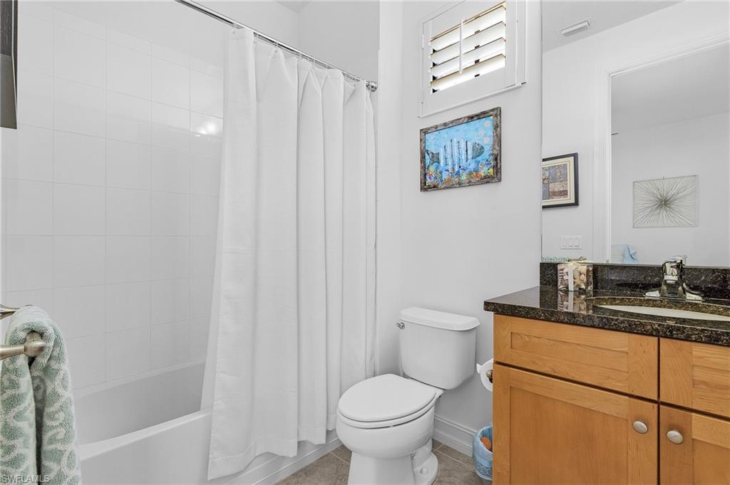 Full bathroom featuring vanity, toilet, shower / tub combo with curtain, tile patterned flooring, and baseboards