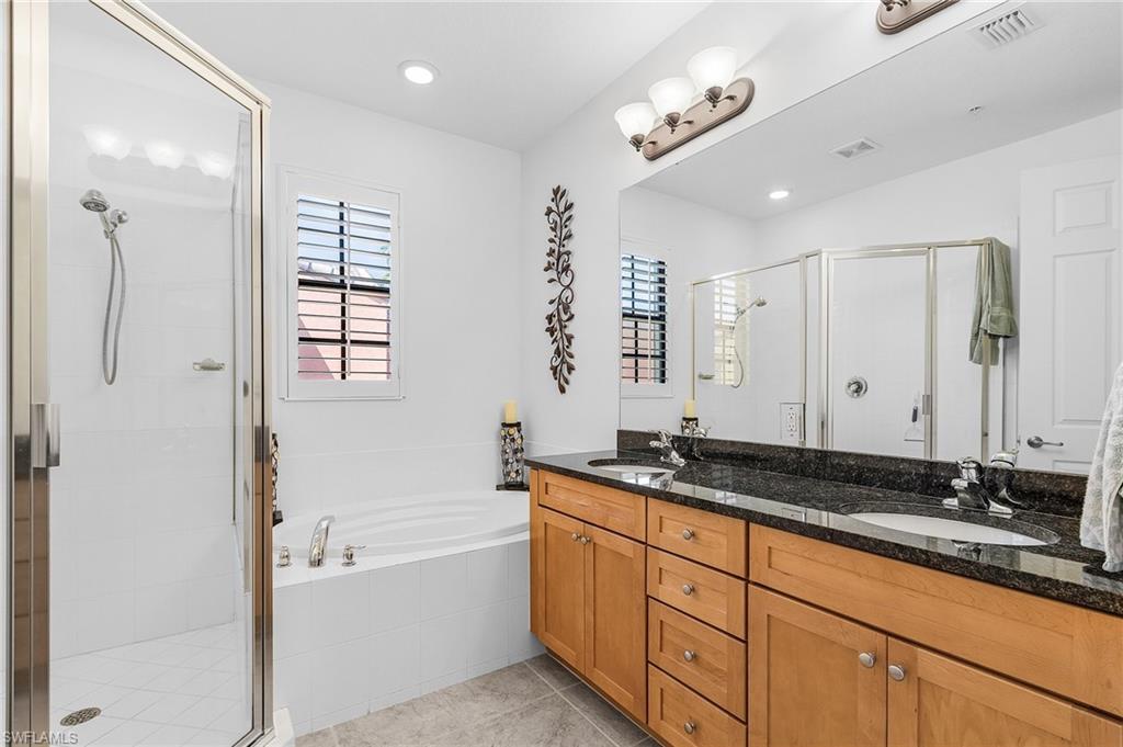 Bathroom with a stall shower, double vanity, a bath, and plenty of natural light