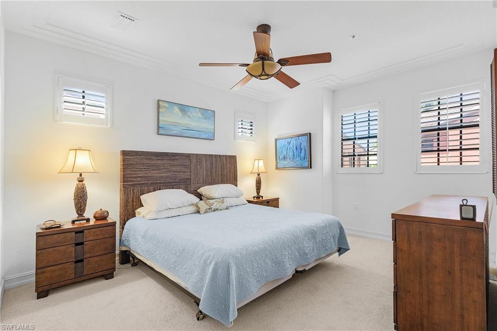 Bedroom featuring light carpet, ornamental molding, baseboards, and ceiling fan