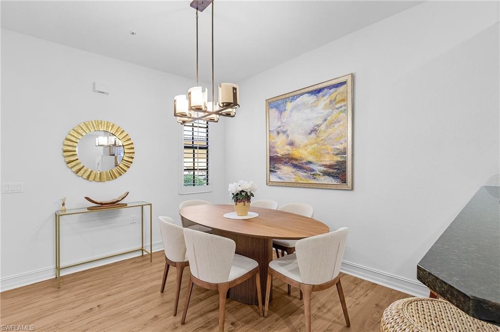 Dining area featuring light wood-style flooring, a chandelier, and baseboards