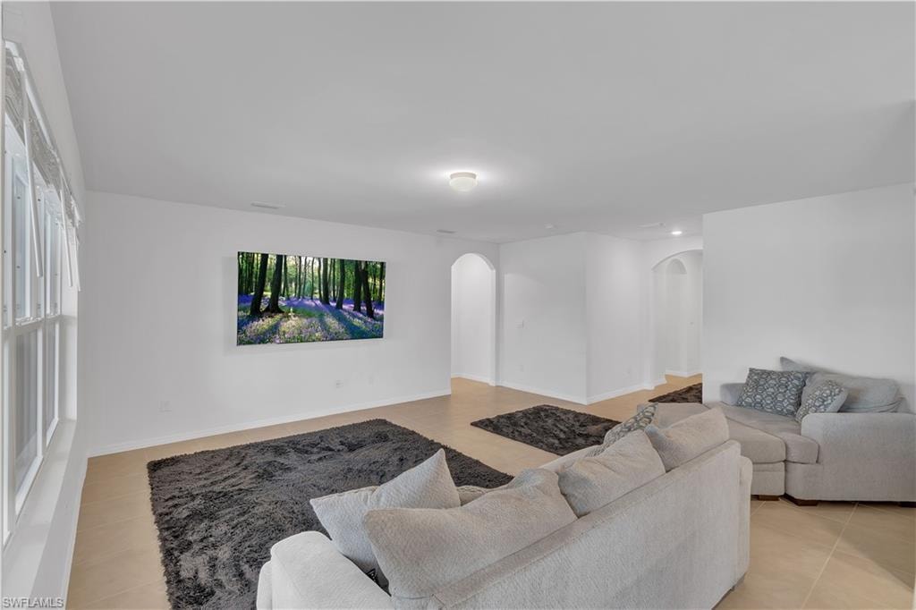 Living room with light tile patterned floors and arched walkways