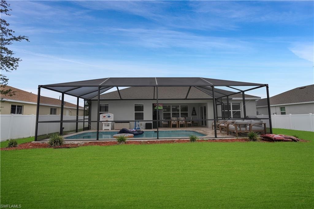Rear view of property featuring a fenced backyard, a sunroom, glass enclosure, and a patio