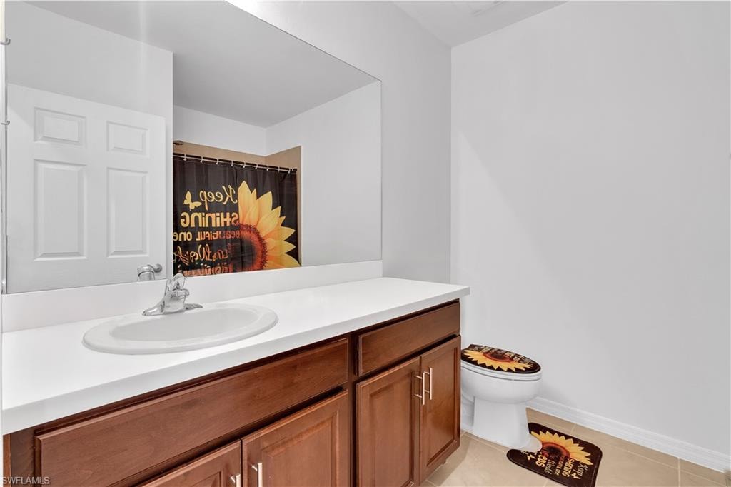 Bathroom featuring light tile patterned floors, vanity, and curtained shower
