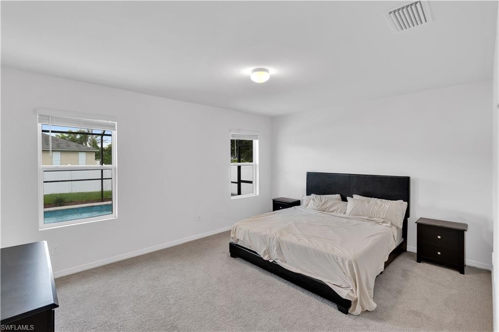Bedroom with light colored carpet and baseboards