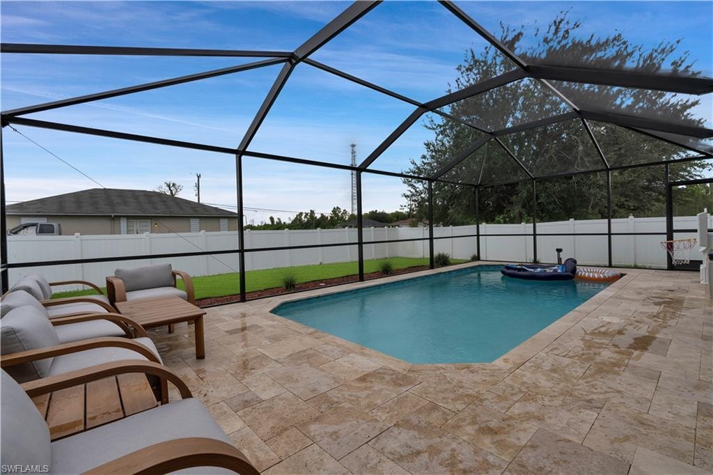 View of swimming pool featuring a fenced backyard, a sunroom, glass enclosure, and a patio area