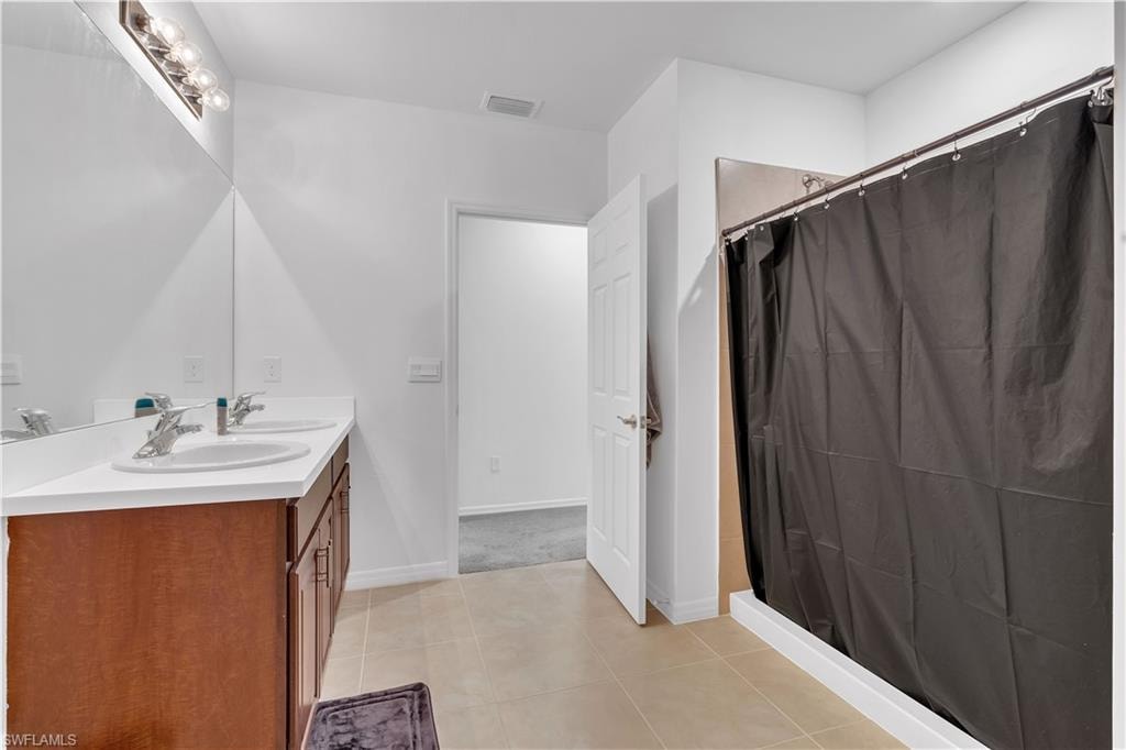 Bathroom featuring double vanity, light tile patterned flooring, and a shower with curtain