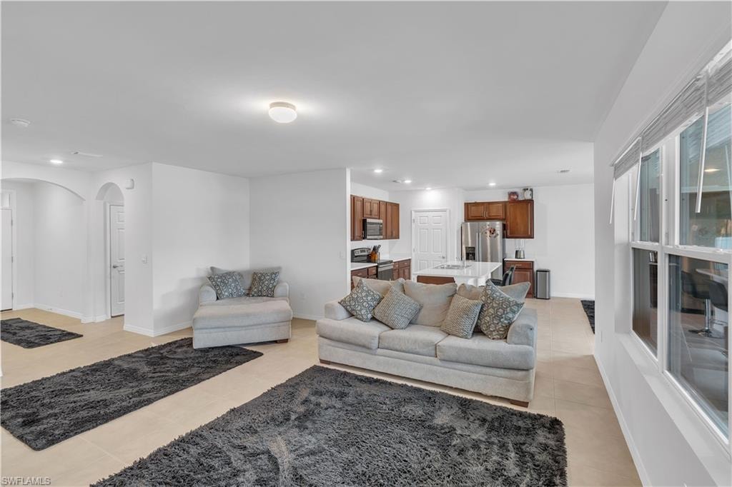 Living area with arched walkways, light tile patterned floors, and recessed lighting