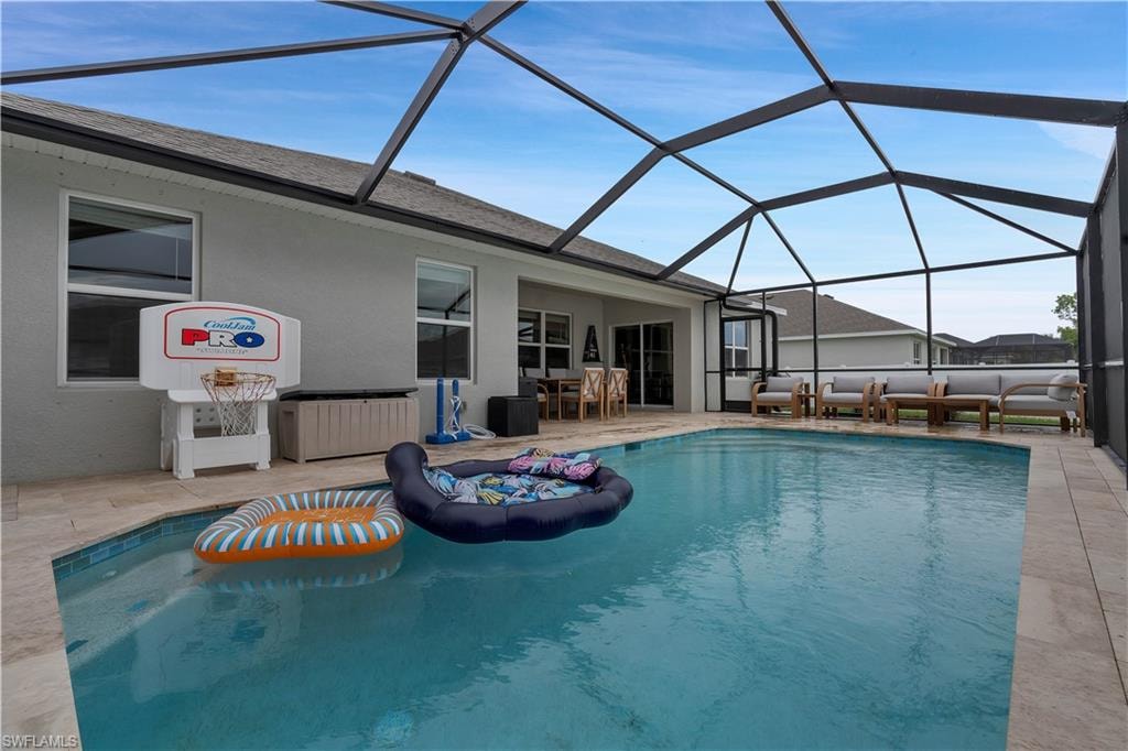Swimming pool featuring a sunroom, a patio area, and glass enclosure