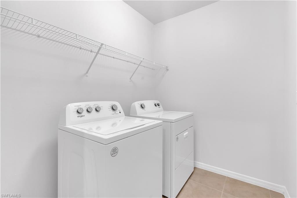 Washroom with light tile patterned flooring and independent washer and dryer