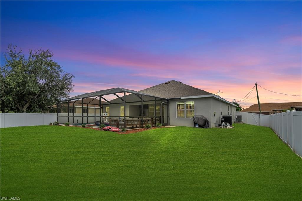 Rear view of property with a fenced backyard, a sunroom, glass enclosure, and stucco siding