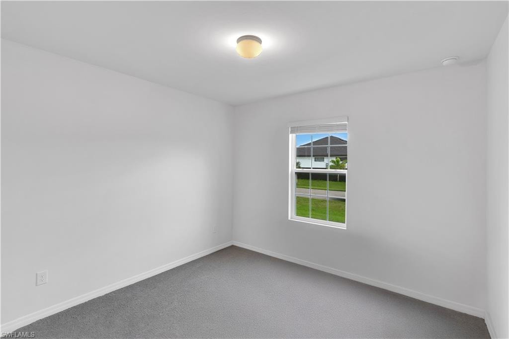 Empty room featuring carpet and baseboards