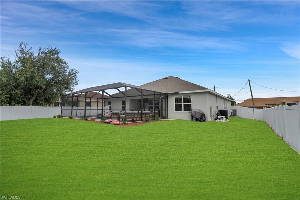 Rear view of property with a fenced backyard, a sunroom, glass enclosure, and stucco siding
