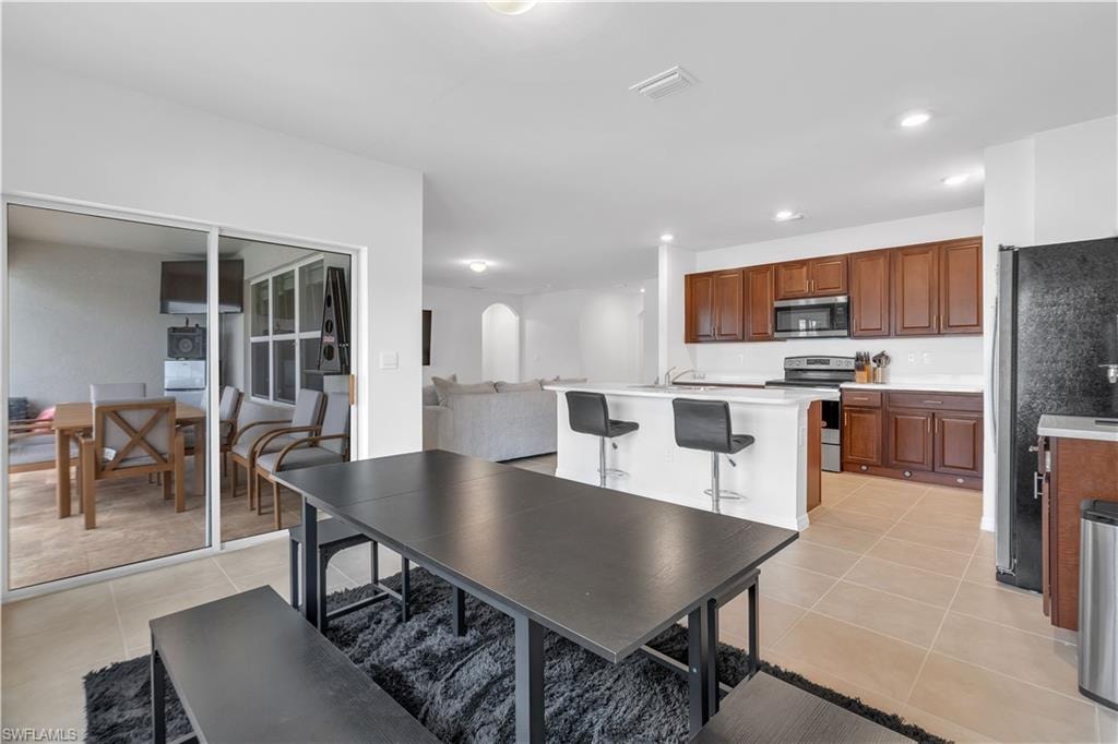 Dining area with light tile patterned flooring and recessed lighting
