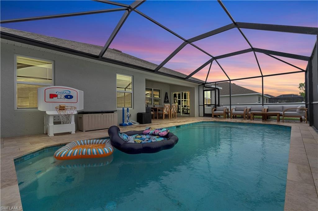 Pool at dusk featuring an outdoor pool, a sunroom, a lanai, and a patio area