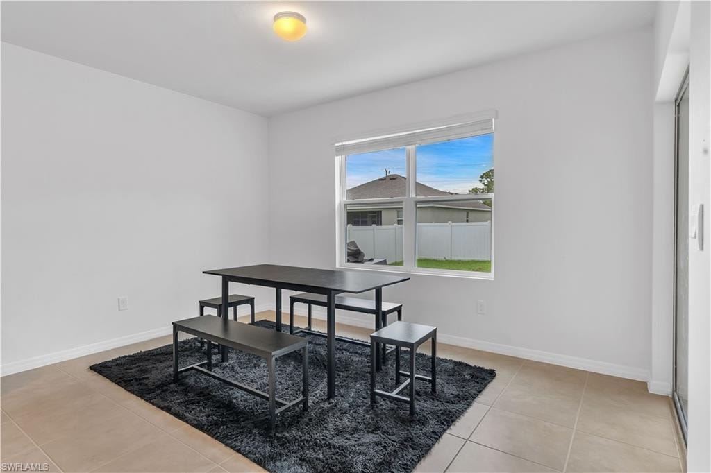 Dining space with light tile patterned flooring and baseboards