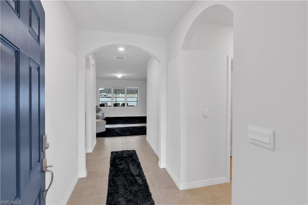 Hall with arched walkways and light tile patterned flooring