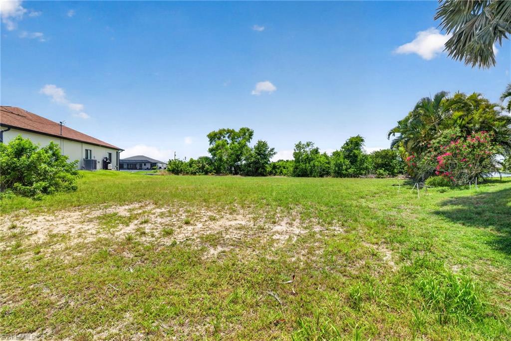 Expansive grass and sand lot with mature trees framing the perimeter