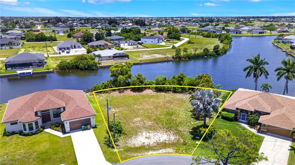 Cleared residential lot featuring mature palm trees and canal access