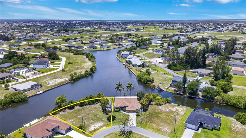 Canal-front property featuring a single-story residence with a tan exterior and a paved driveway