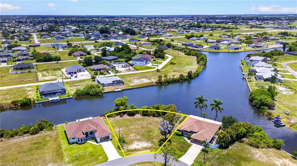 Canal-front lot featuring a partial cul-de-sac location, mature palm trees, and established residential surroundings