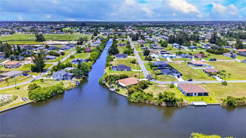 Residential area featuring a canal waterway, waterfront properties, and scattered mature trees
