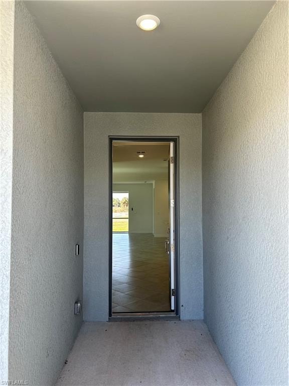 Entryway featuring a recessed light fixture, textured stucco walls, and a concrete landing