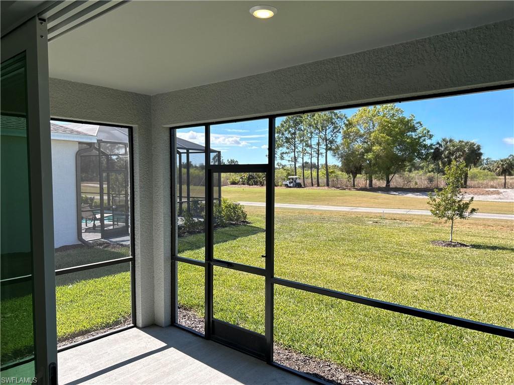Screened-in outdoor living space featuring concrete flooring, a recessed ceiling light, and an expansive lawn