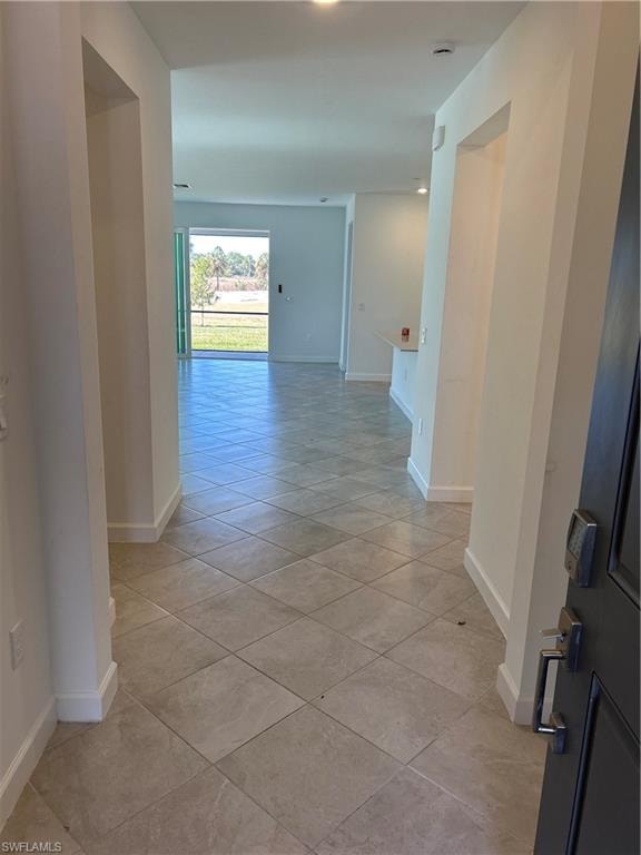 Spacious entryway featuring light-toned square tile flooring, white baseboards, and a recessed wall niche