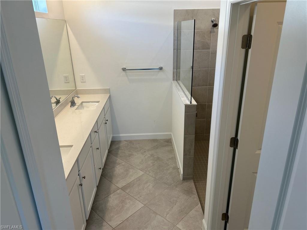 Bathroom featuring a dual vanity with light-toned countertops, integrated sinks, and polished chrome fixtures
