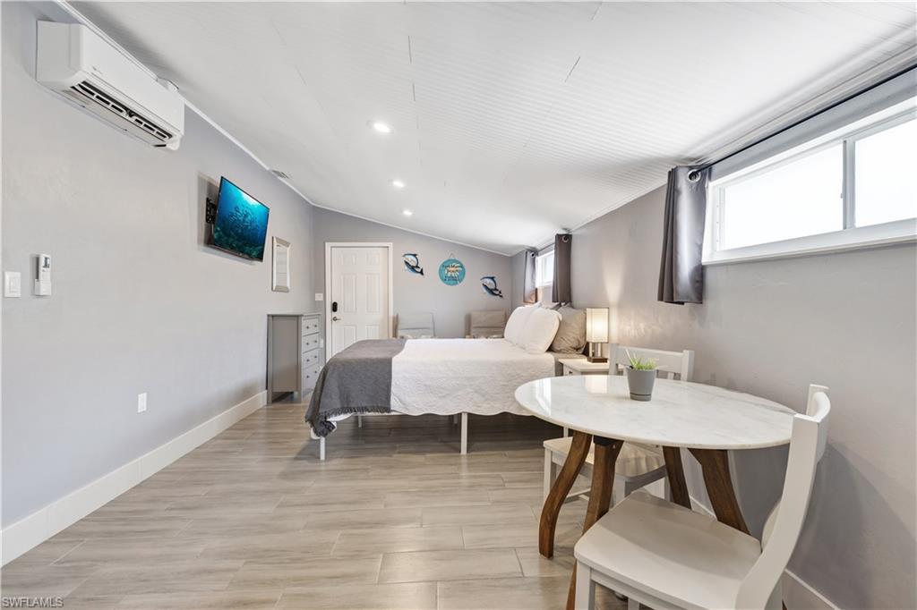 Open-concept room featuring light gray walls, wood-finish flooring, and a sloped ceiling with recessed lighting