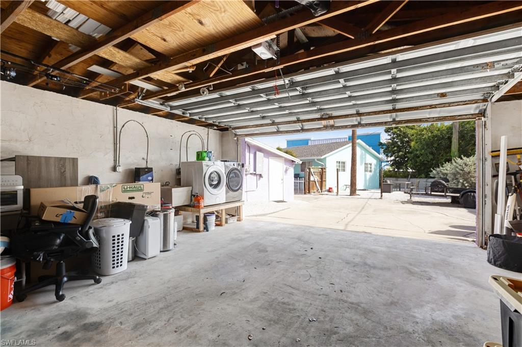 Spacious garage featuring a concrete floor, exposed wood beam ceiling, and overhead garage door