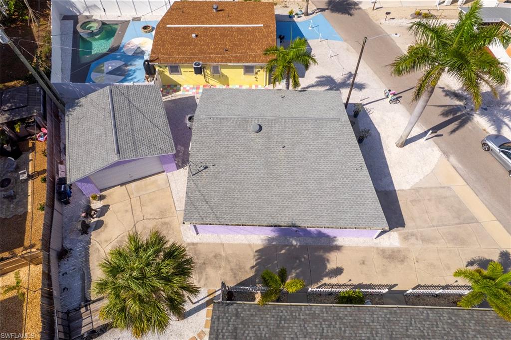 Property with shingle roof and purple trim, featuring a concrete driveway and mature palm tree landscaping