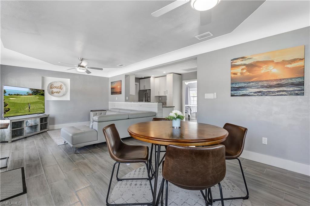 Open-concept living space featuring wood-look tile flooring, contemporary ceiling fans, and a dining area with a round wood-finish table