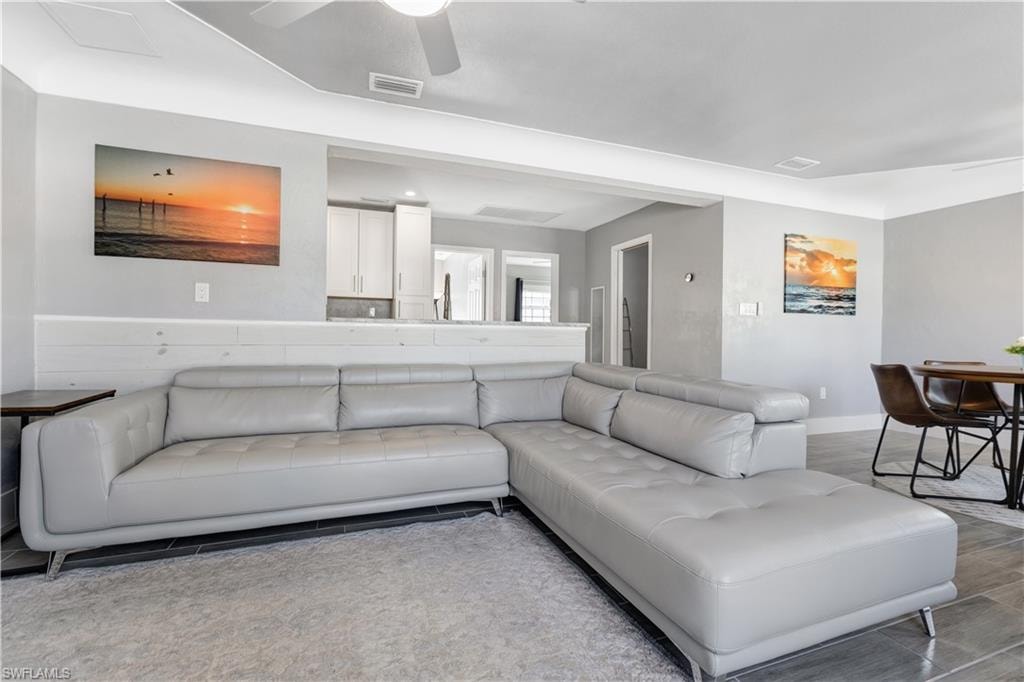 Open-concept living area featuring a pass-through window to the kitchen, crown molding, a built-in shiplap accent wall, and recessed lighting
