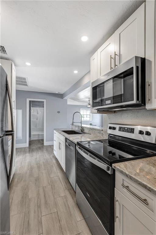 Modern kitchen featuring stainless steel appliances, white shaker cabinetry, and light-toned countertop surfaces