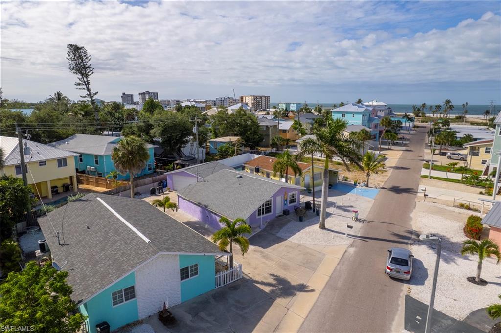 Coastal neighborhood featuring an array of colorful residences, mature palm trees, paved streets, and shell-covered landscaping
