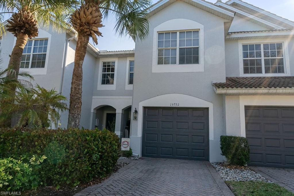 Traditional-style house with stucco siding, decorative driveway, and a garage