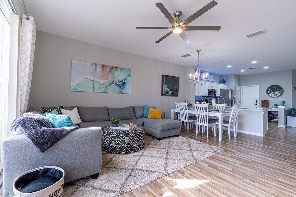 Living room featuring light wood-style floors, a ceiling fan, and a chandelier