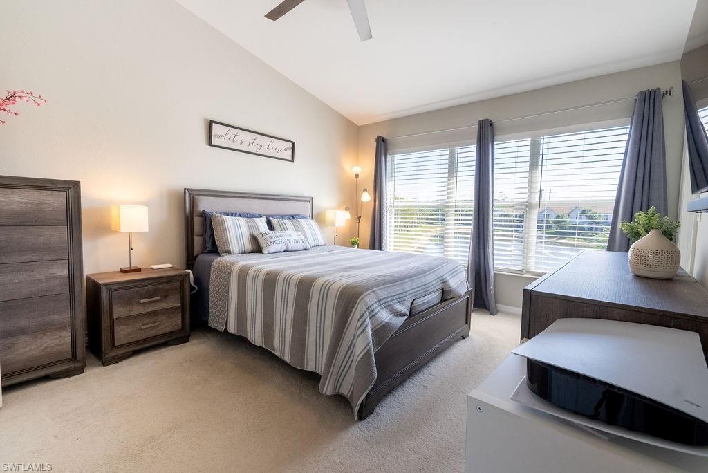 Bedroom featuring vaulted ceiling, light colored carpet, and a ceiling fan