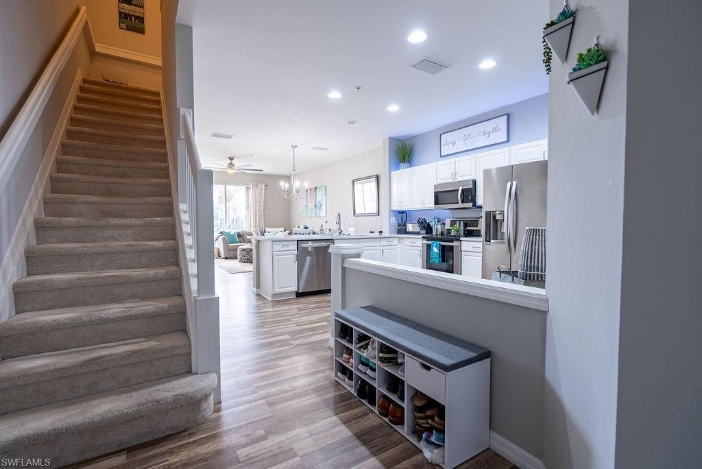 Staircase with wood finished floors, recessed lighting, and a chandelier