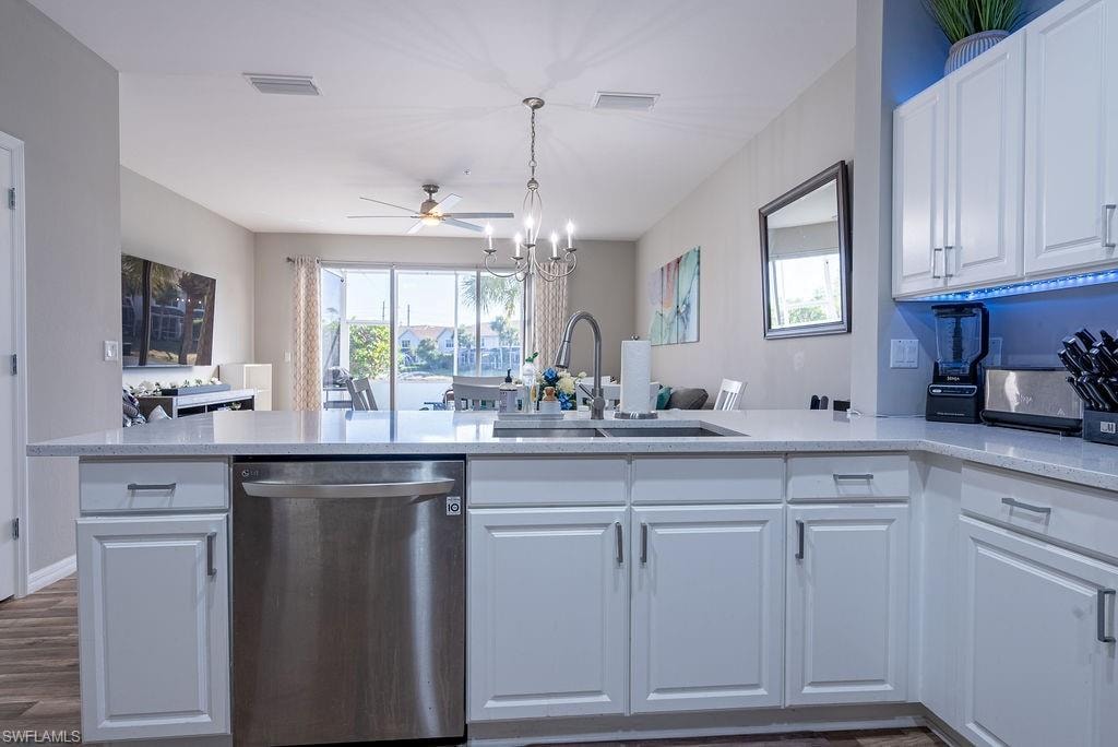 Kitchen with open floor plan, dishwasher, white cabinets, light stone counters, and ceiling fan
