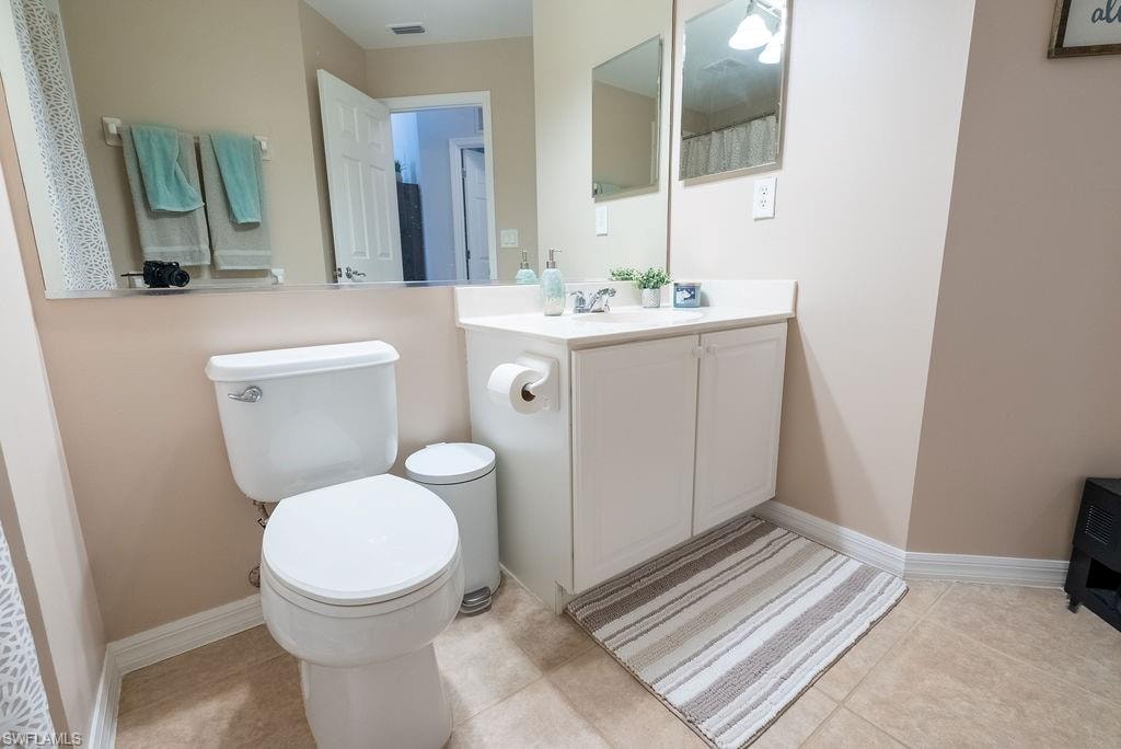 Full bathroom with vanity, light tile patterned flooring, and curtained shower