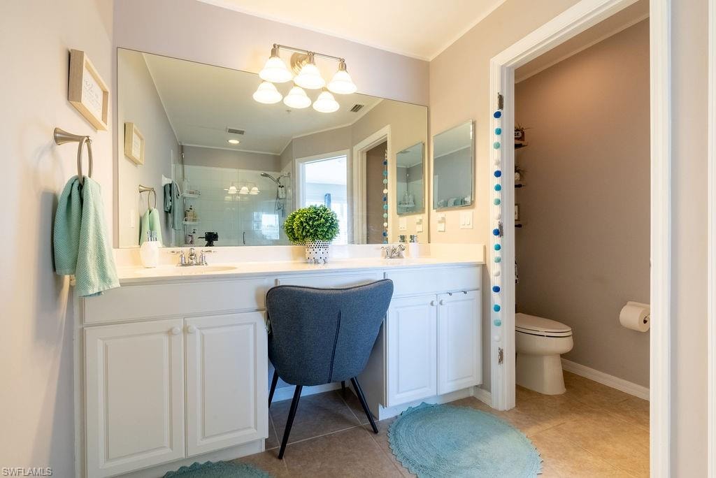Full bath featuring a shower stall, double vanity, and light tile patterned flooring