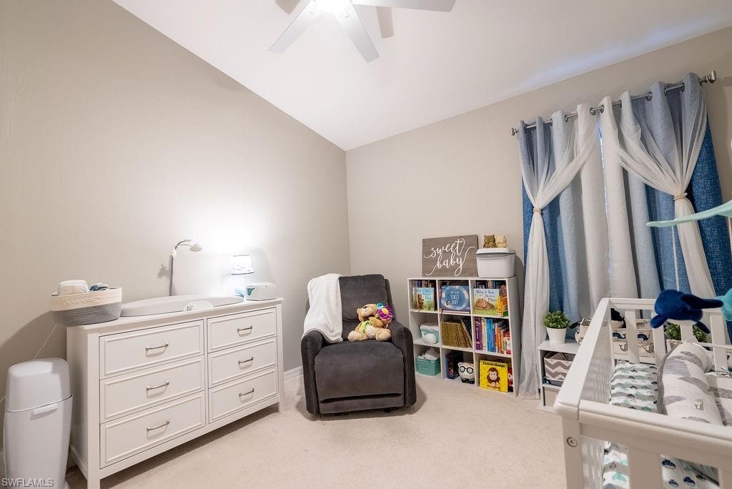 Bedroom featuring light colored carpet, lofted ceiling, and ceiling fan