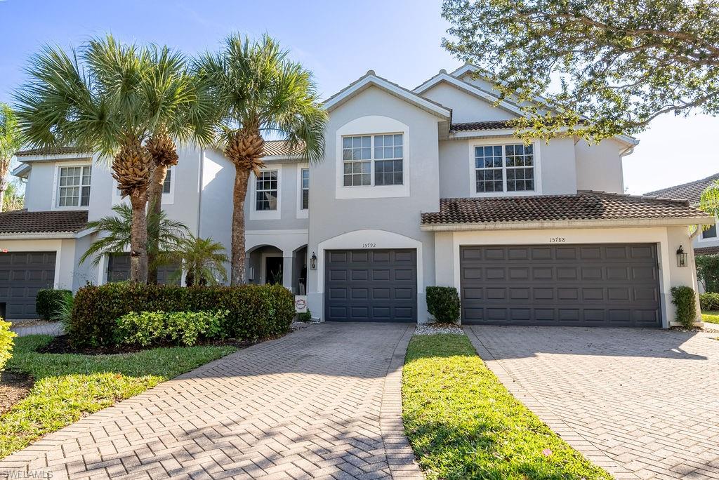 View of front of home featuring decorative driveway, a garage, stucco siding, and a tiled roof