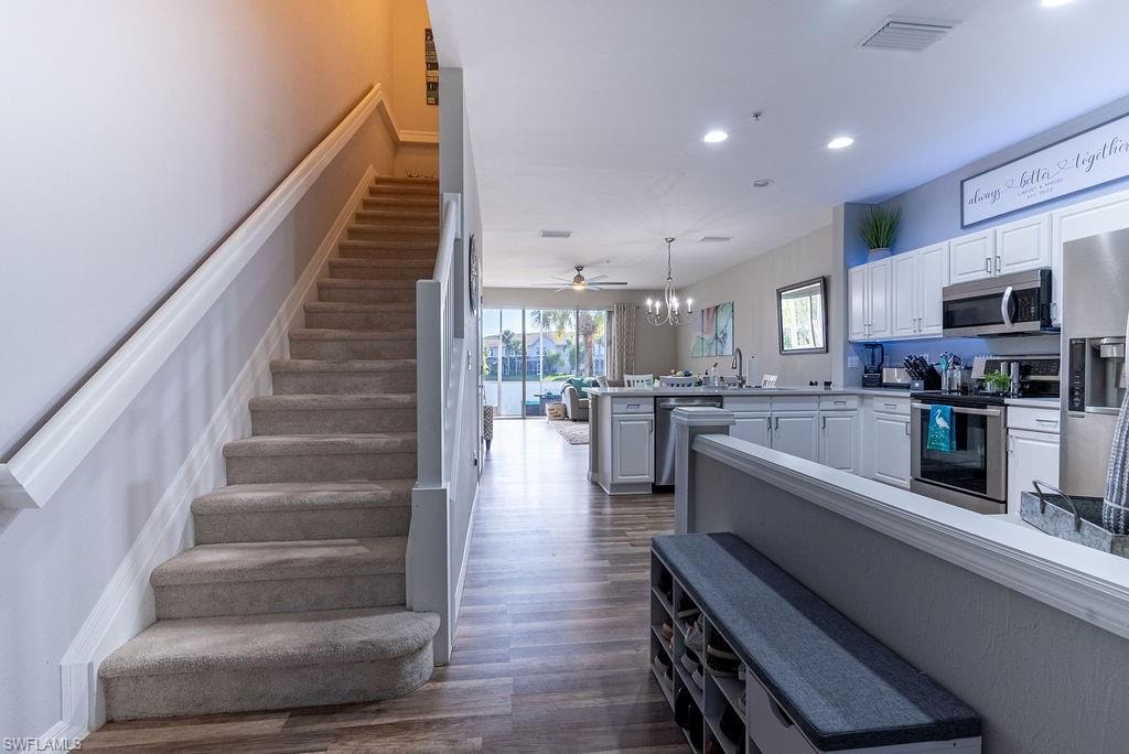 Stairs with wood finished floors, recessed lighting, and ceiling fan