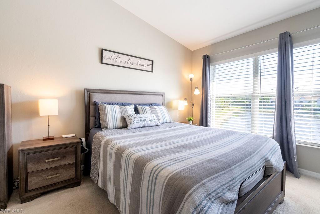 Bedroom with light carpet and lofted ceiling