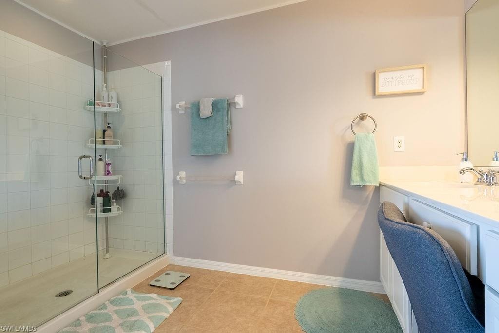 Full bath with vanity, a stall shower, ornamental molding, and light tile patterned floors
