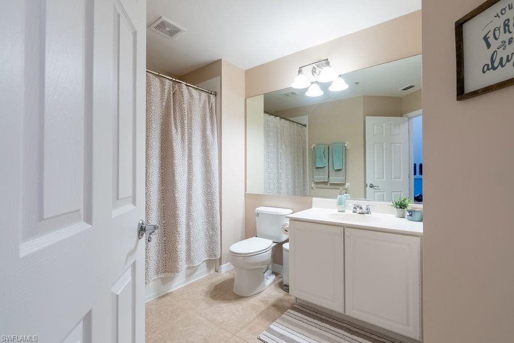 Bathroom featuring vanity, light tile patterned floors, and shower / bath combination with curtain